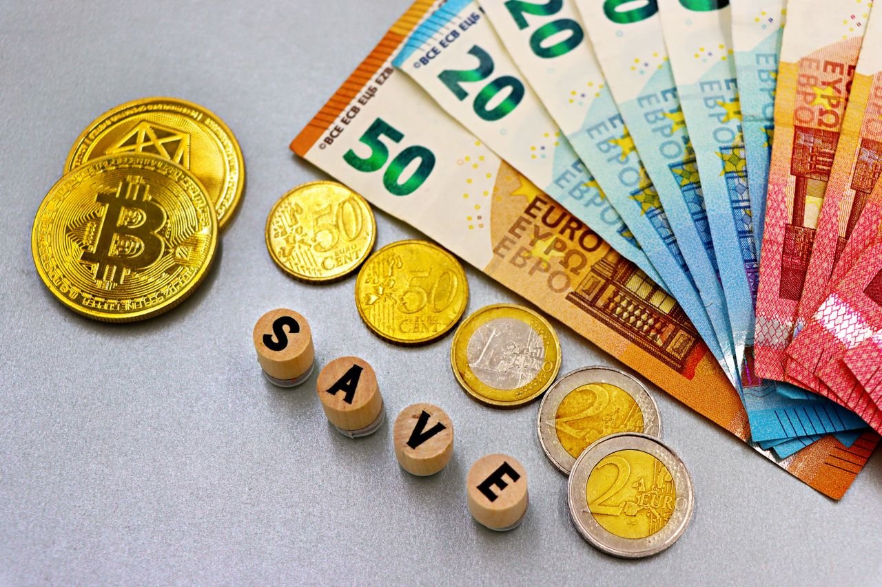 Euro banknotes and Bitcoin coins arranged with 'save' text for finance concept.